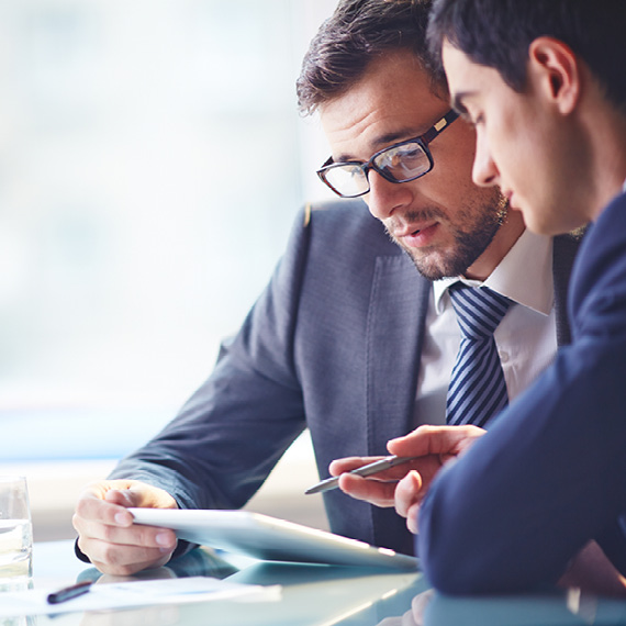 Male coworkers reviewing compliance regulations on a tablet